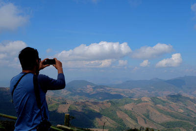 Man photographing against sky