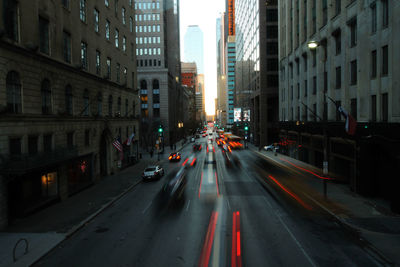 Blurred motion of cars on road amidst buildings in city