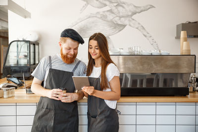 Chefs holding digital tablet standing at kitchen