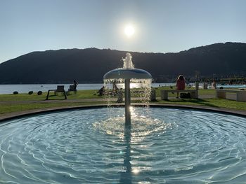 People by swimming pool against clear sky