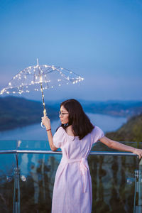 Woman standing by railing against sky