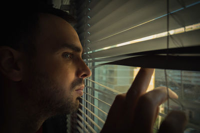 Close-up of man looking through window