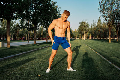 Rear view of shirtless man running on field