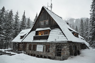 Built structure on snow covered land by houses against mountain