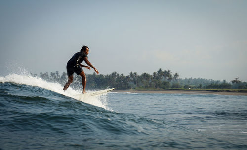 Man surfing in sea against sky