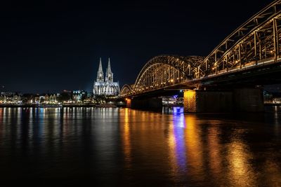 Illuminated bridge over river at night