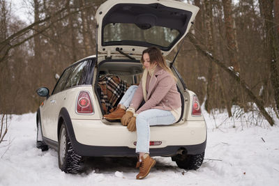 Portrait of young woman sitting in car trunk