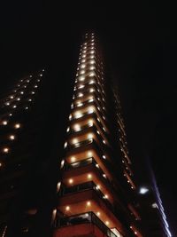 Low angle view of illuminated skyscraper against sky at night