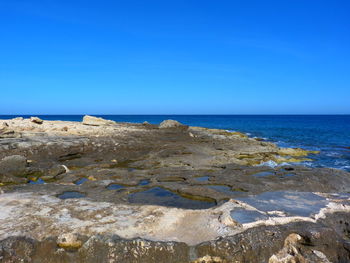 Scenic view of beach against clear blue sky