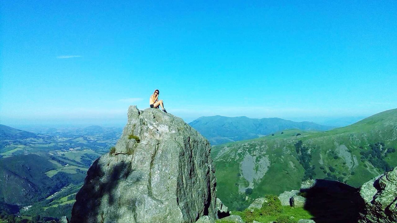 mountain, leisure activity, lifestyles, clear sky, tranquility, tranquil scene, blue, scenics, copy space, beauty in nature, men, nature, landscape, rear view, hiking, full length, mountain range, tourism