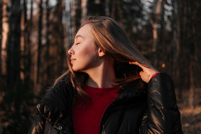 Young woman looking away while standing in forest