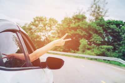 Cropped hand gesturing in car on road