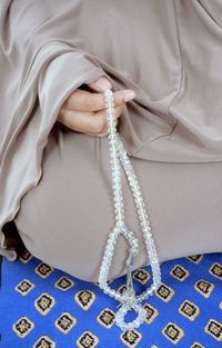 Midsection of woman holding rosary and praying