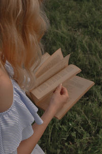 Midsection of woman reading book on field