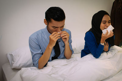 Young couple sitting on bed at home