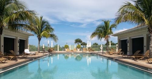 Palm trees by swimming pool against sky