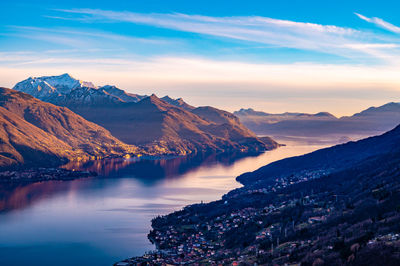 View of lake como at dusk, towards the south, from musso, with the mountains above and the towns.