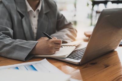 Midsection of businessman using laptop on table