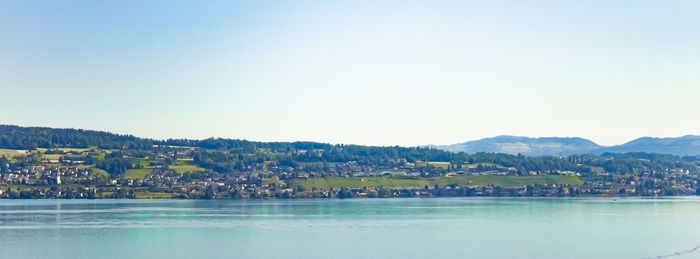 Scenic view of townscape by mountains against clear sky