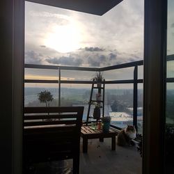 Chairs and table by sea against sky during sunset