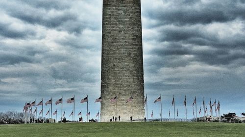 Low angle view of cemetery on field against cloudy sky