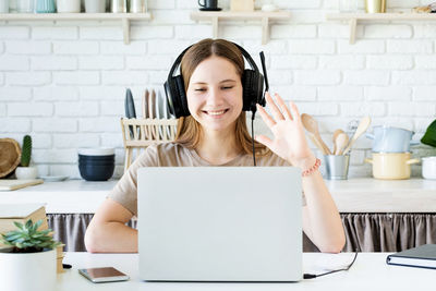 Portrait of smiling young woman using laptop on table