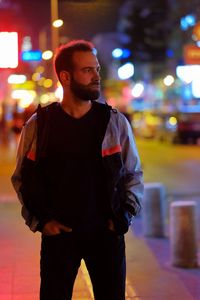 Portrait of young man looking away in city at night