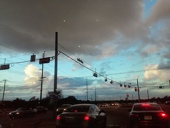 Cars moving on road against cloudy sky