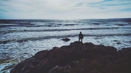 Man standing on rock by sea