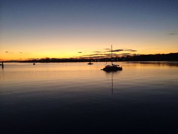 Silhouette ship in water against sky during sunset