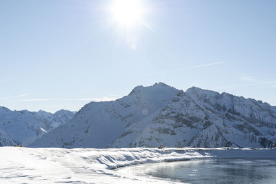 Scenic view of snowcapped mountains against sky on sunny day