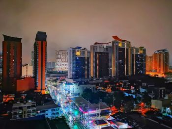 Illuminated buildings in city against sky at night