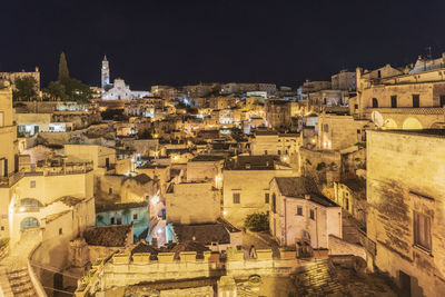 Rear view of townscape against illuminated buildings in city at night
