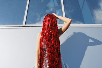 Woman covered with red decoration by wall