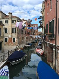 Boats moored in canal amidst buildings in city