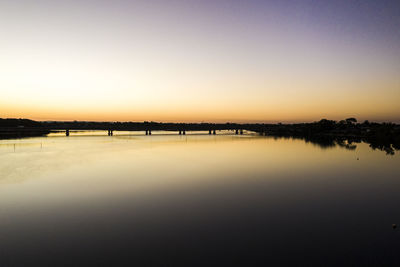 Scenic view of lake against clear sky during sunset