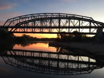 Silhouette bridge over river against sky during sunset