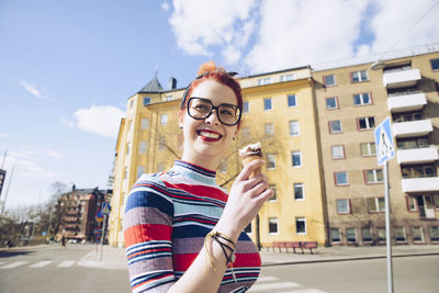 Redhead young woman eating ice cream on city street