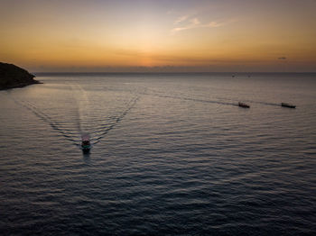 Silhouette person in sea against sky during sunset