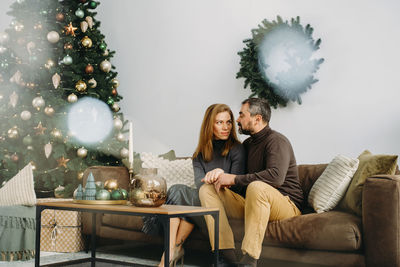 Couple celebrating romantic christmas eve at home. christmas interior decoration for family party