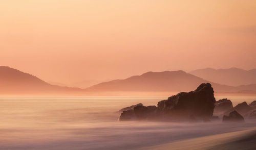 Scenic view of sea and mountains against sky during sunset