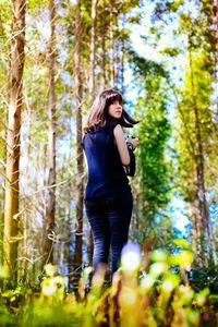 Woman standing by tree trunk in forest