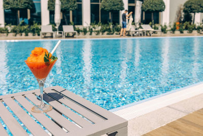 Fresh red cocktail with ice in glass on swimming pool. tropical juice on luxury 
