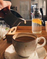 A woman's hand pours milk into coffee