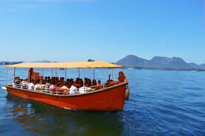People traveling in boat at lake against sky