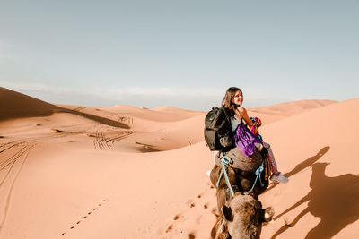 Female tourist riding a camel in the middle of the sahara desert
