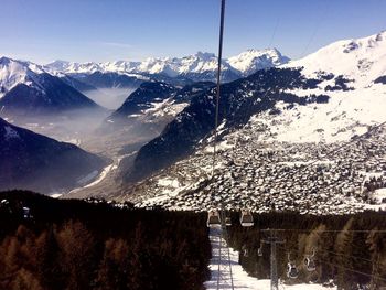 Scenic view of snowcapped mountains against sky and city