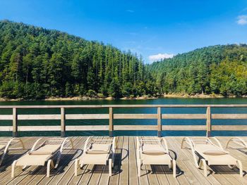 Empty sunbeds on wooden pontoon near the lake on a day with clear blue sky