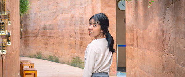 Portrait of woman standing against wall