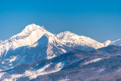 Scenic view of snowcapped mountains against clear blue sky